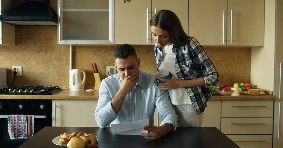 Homeowner reviewing mortgage documents and late notices at a kitchen table