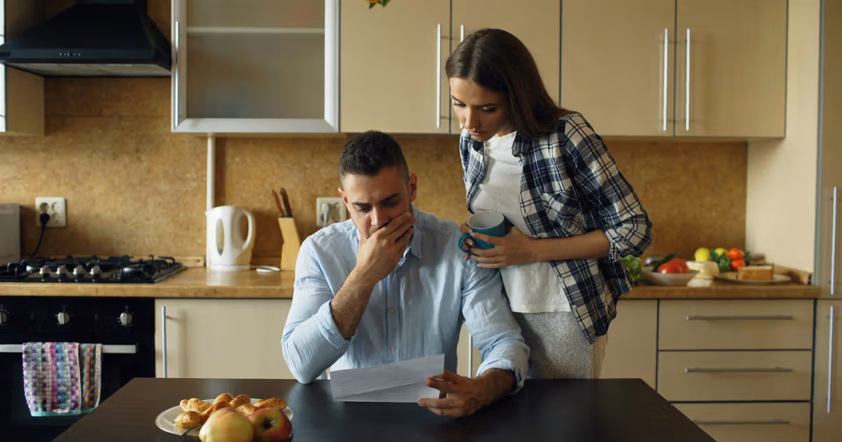 Homeowner reviewing mortgage documents and late notices at a kitchen table